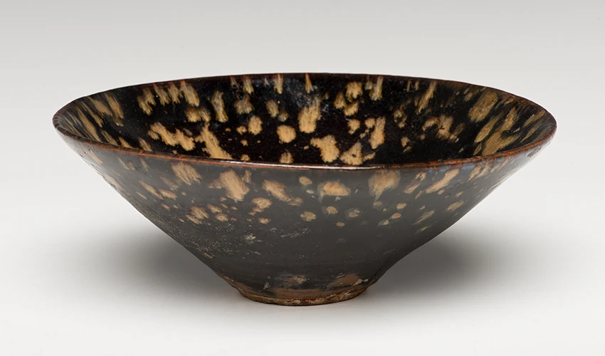 head on and slightly above photo of tortoise shell tea bowl on light gray background